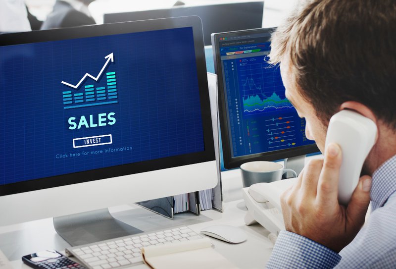 man on telephone in front of a screen reading sales